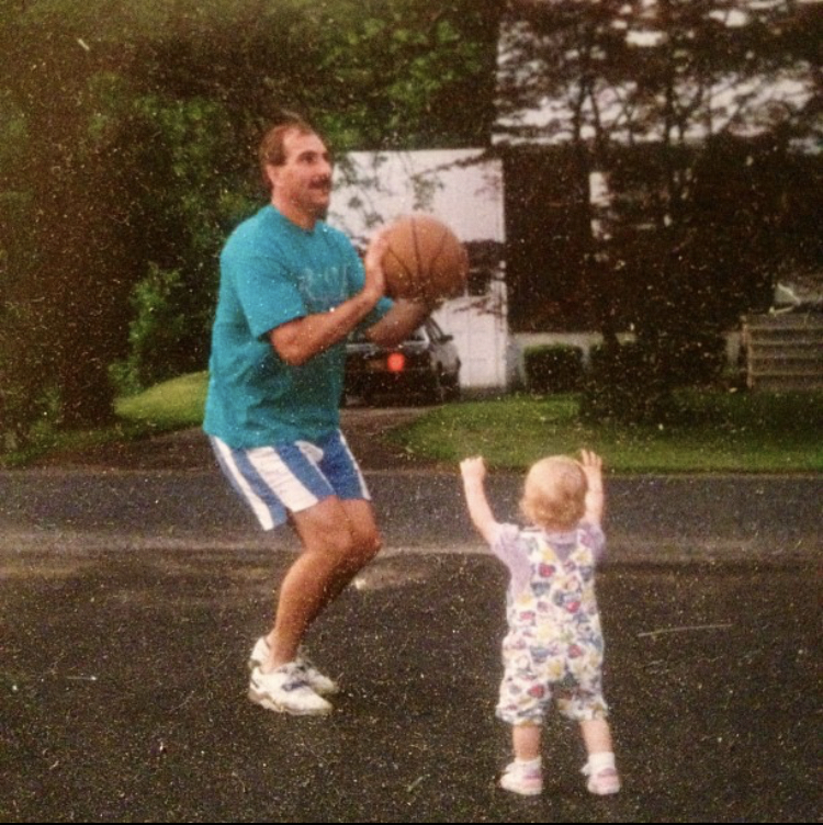 Man shooting a basketball, little girl trying to defend the shot