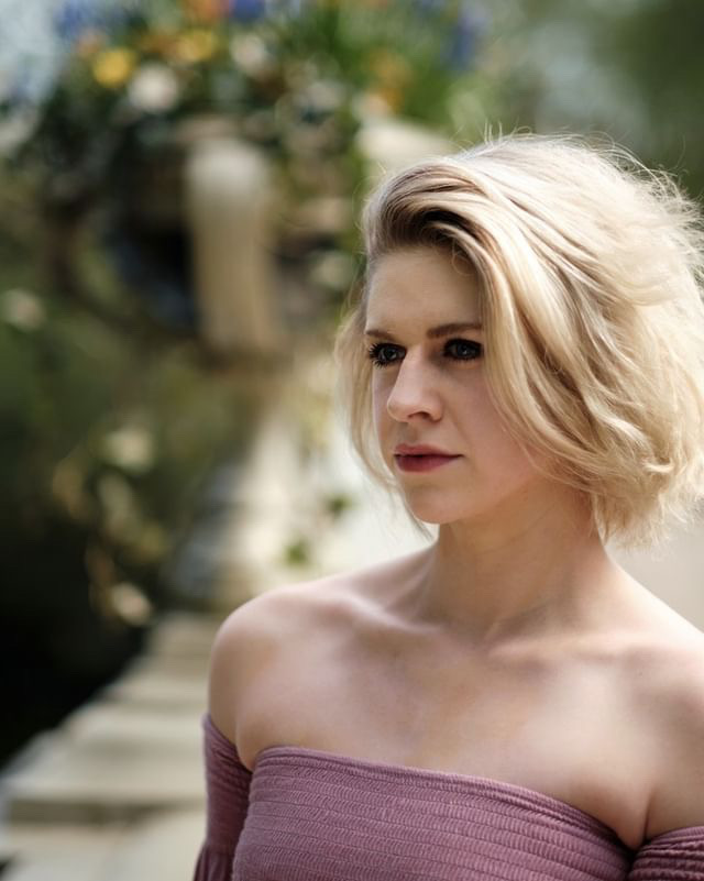 portrait style photo of a blonde girl with short hair looking past the camera