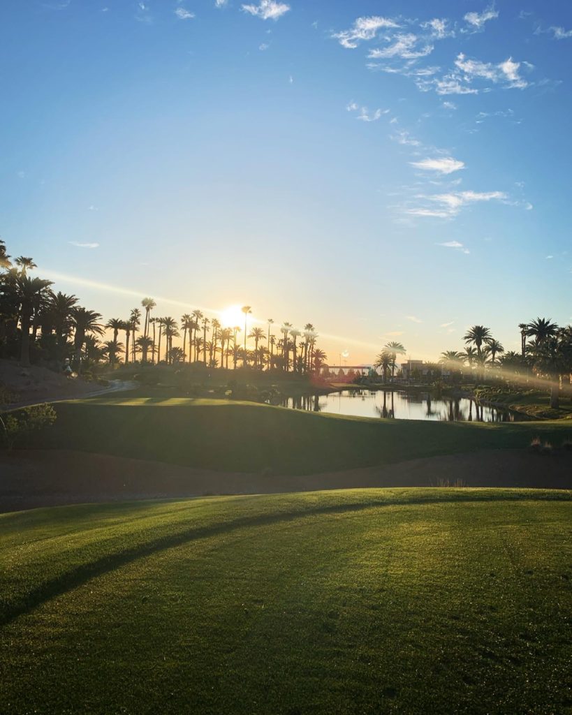 view from a golf course in Vegas, greens and palm trees with the sun peaking out above