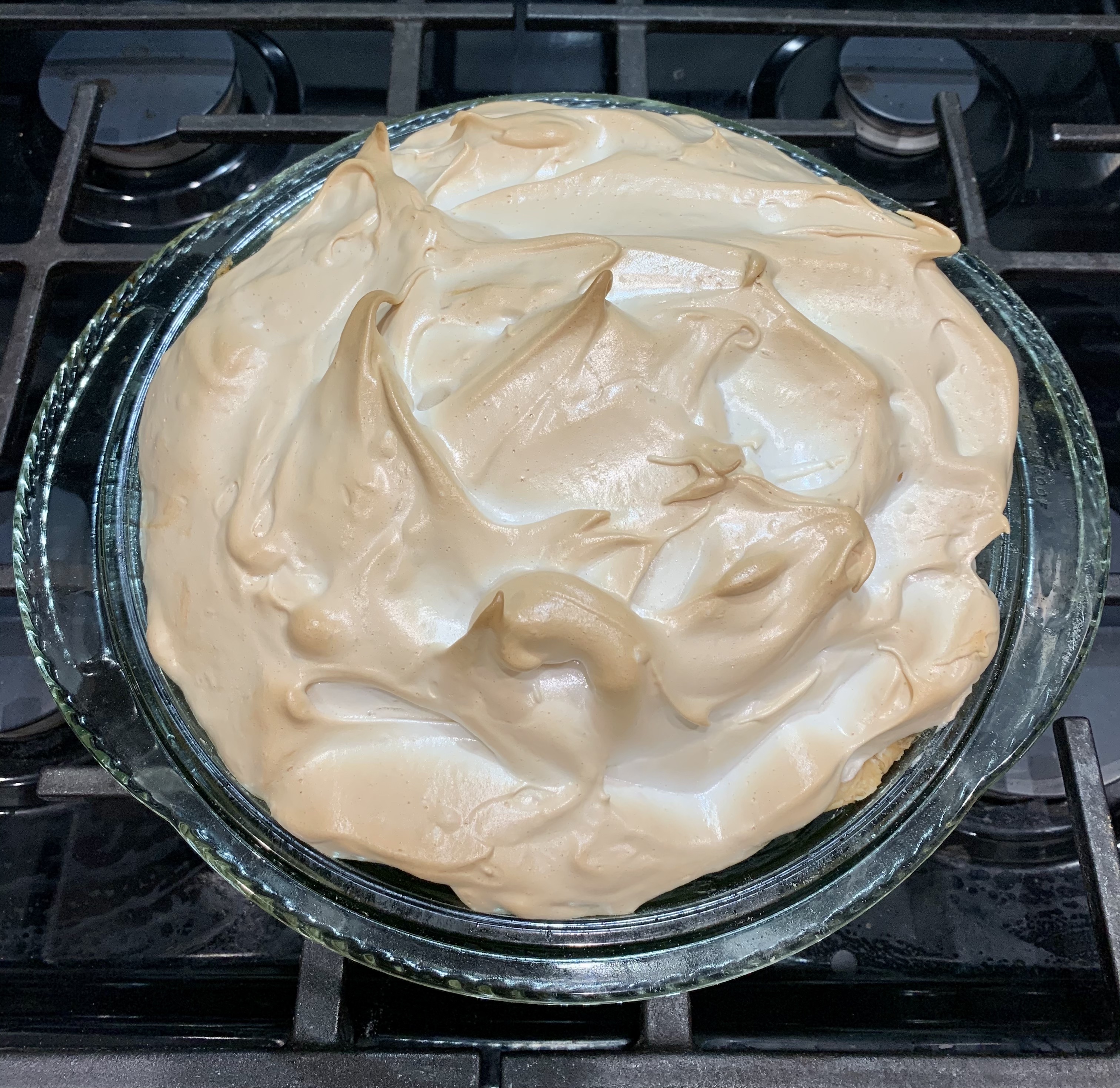 top of lemon meringue pie, white chiffon-like meringue on top, in a glass dish