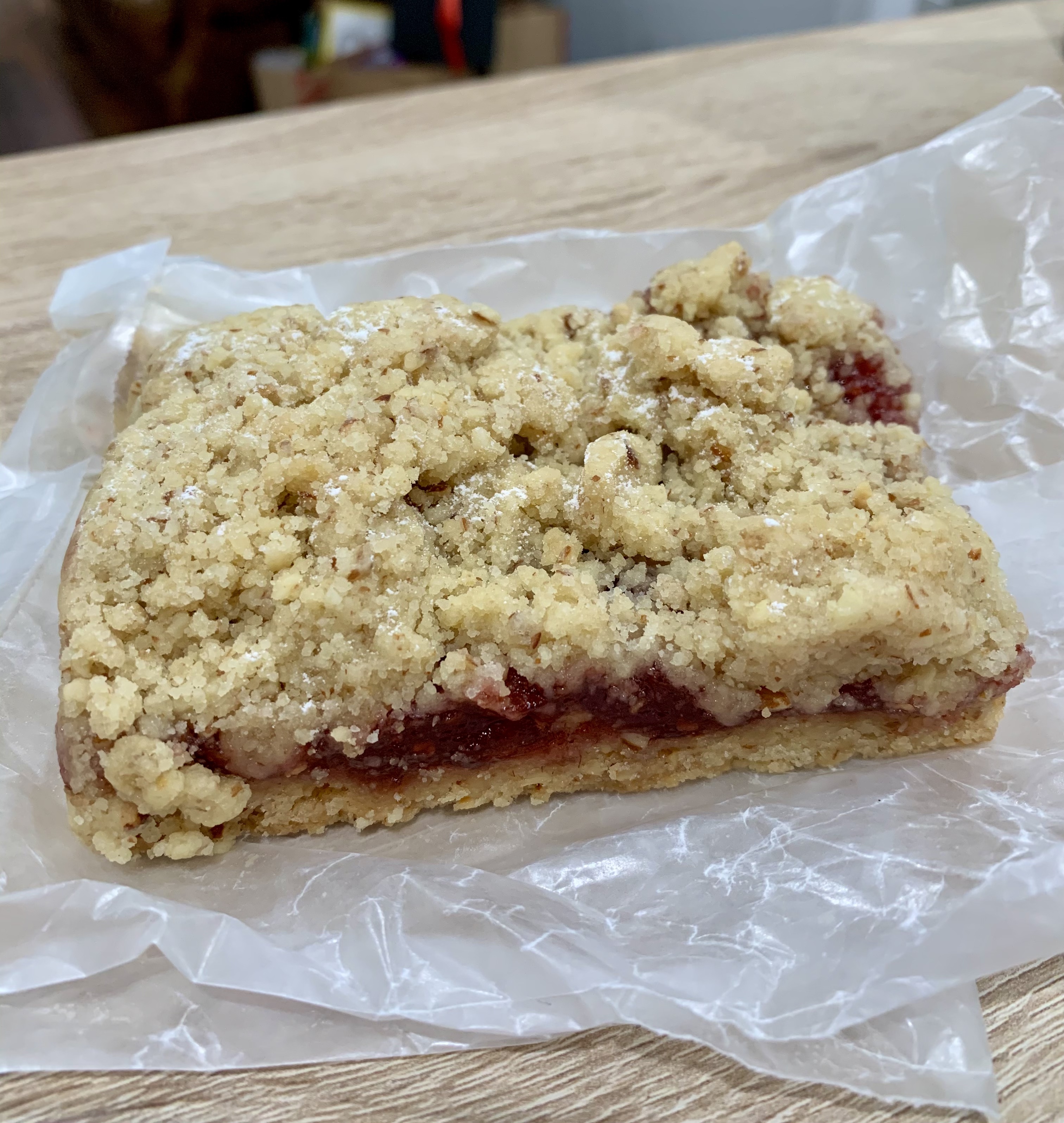 raspberry crumb bar, vegan, sitting atop a piece of wax paper