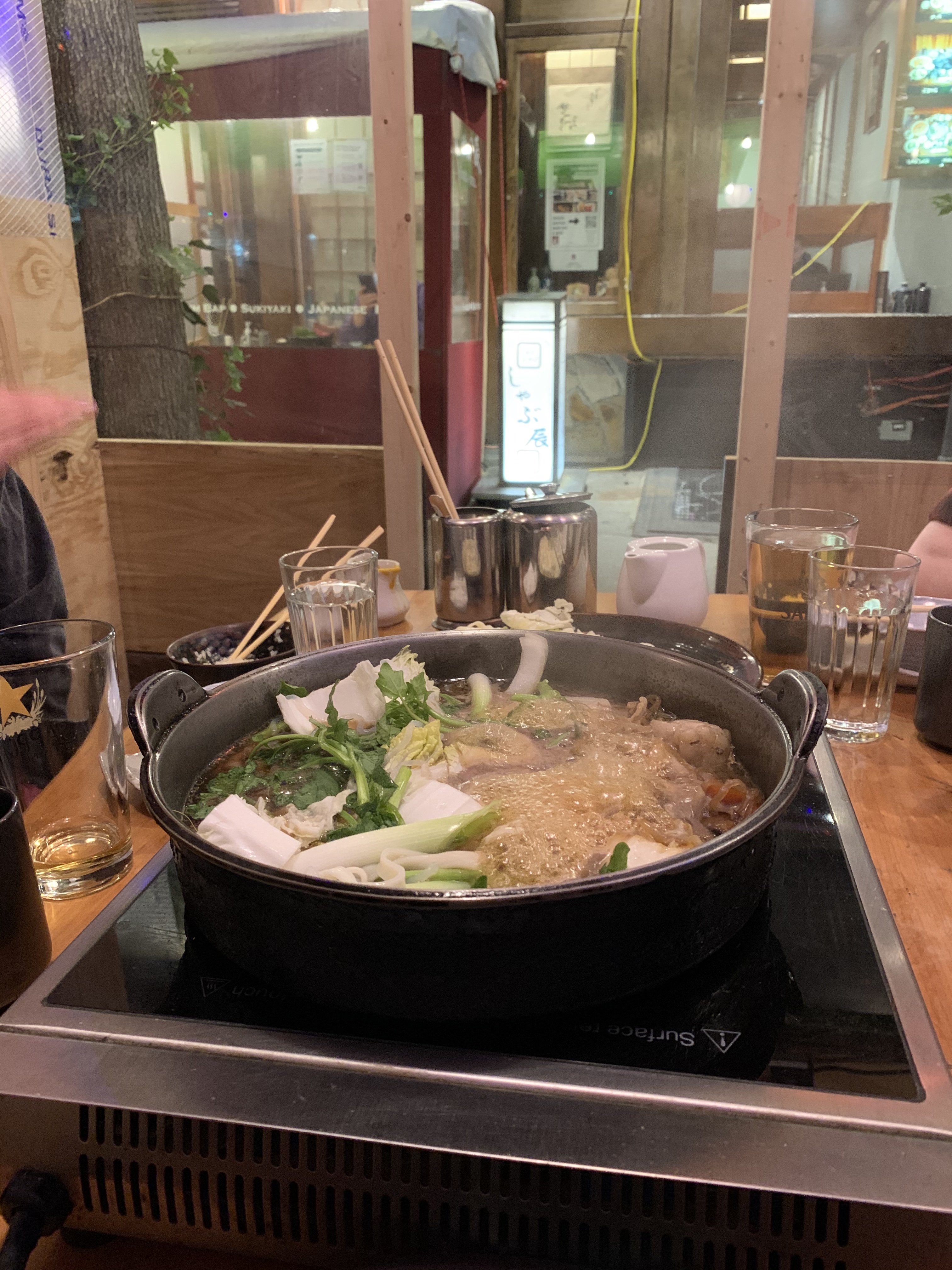 sukiyaki pot boiling, filled with cooking meats and veggies