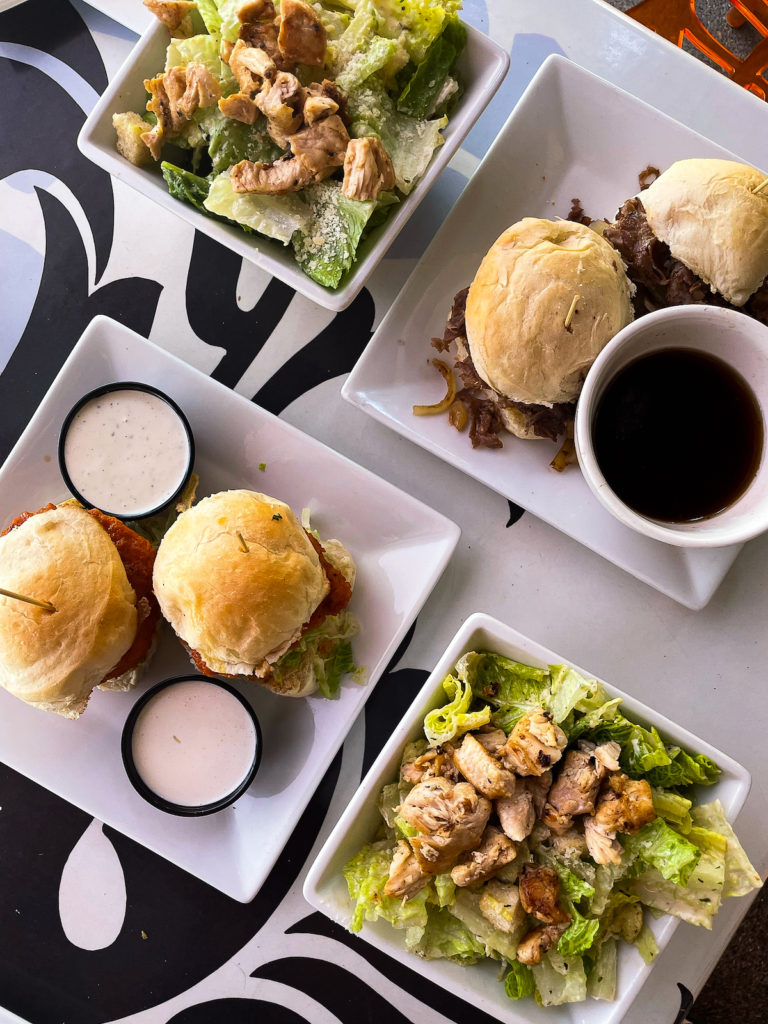 plates of food at a restaurant in Vegas, two plates with sliders, two small white bowls with chicken Caesar salad