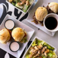 plates of food at a restaurant in Vegas, two plates with sliders, two small white bowls with chicken Caesar salad