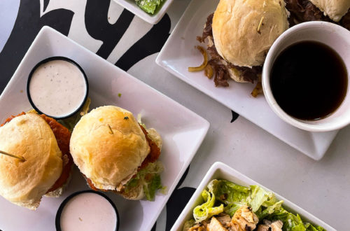 plates of food at a restaurant in Vegas, two plates with sliders, two small white bowls with chicken Caesar salad