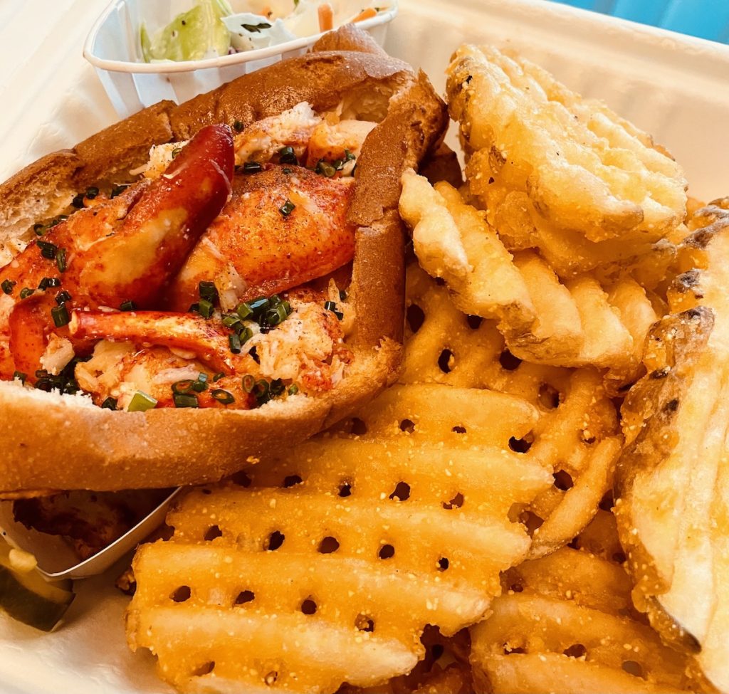 Closeup of a lobster roll with a side of coleslaw and waffle fries, from LobsterMe in the Venetian Las Vegas